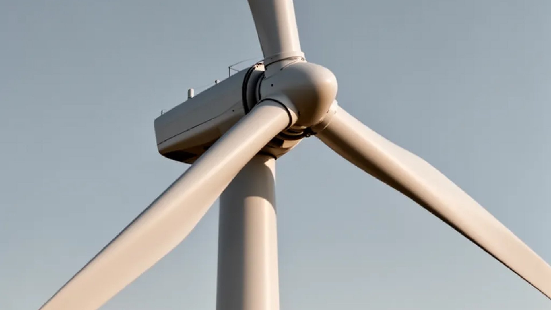 Close-up of a wind turbine hub against pale sky