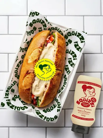 Filled sub roll in Squizzi tray beside a Japanese mayo bottle – squizzi