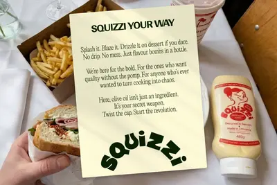 Squizzi Your Way manifesto card on a table with a sandwich and fries – squizzi